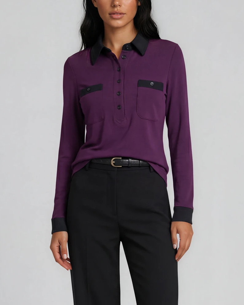 A model stands against a light gray studio background wearing a mulberry purple long-sleeve polo shirt with a black collar and chest pocket trim, black trousers. contrast collar polo - pete collection